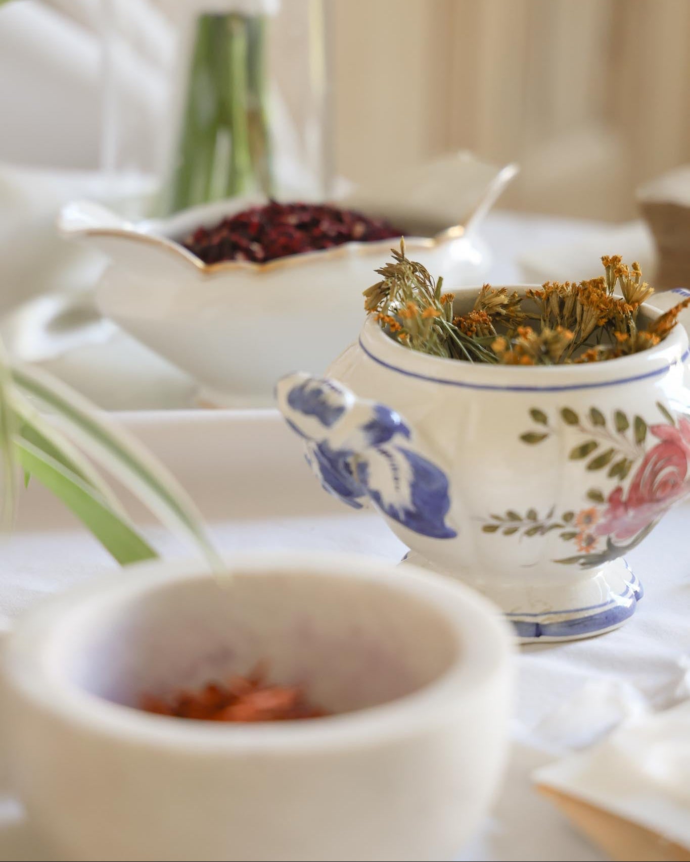 Tea-making setup with a teapot, bowls, and tea leaves on a white surface.