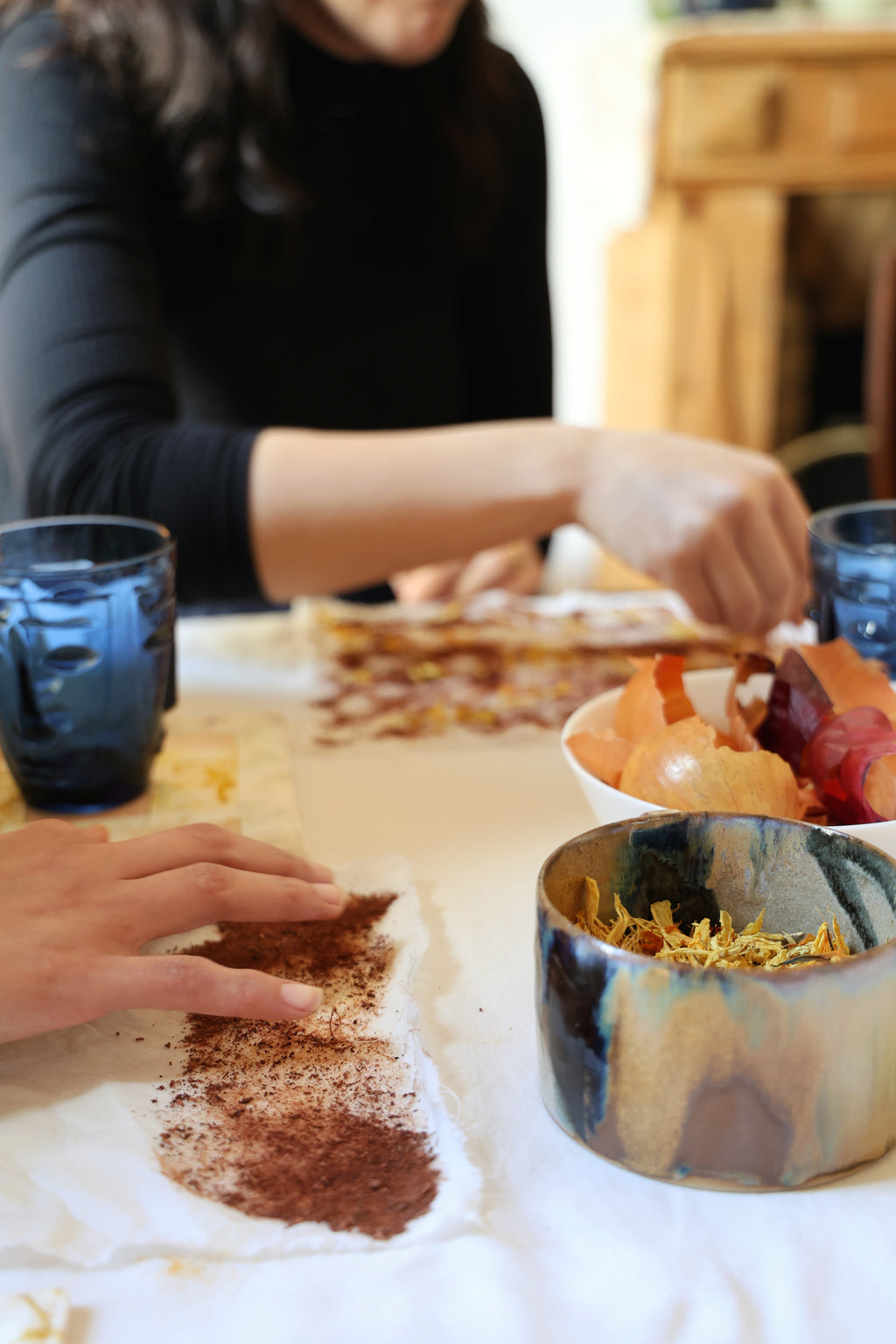 Hands applying natural plant pigments onto fabric during an ecoprint workshop in Paris — Florilegium Paris